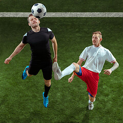 Image showing Football players tackling ball over green grass background