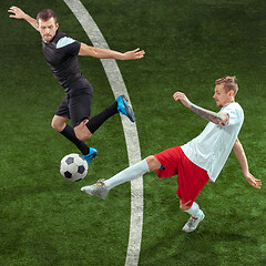 Image showing Football players tackling ball over green grass background