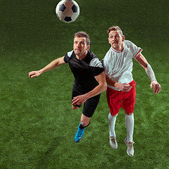 Image showing Football players tackling ball over green grass background