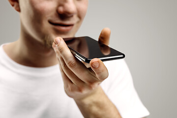 Image showing Indoor portrait of attractive young man holding smartphone