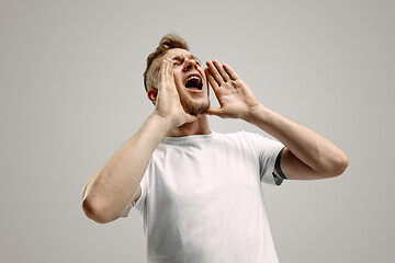 Image showing Isolated on gray young casual man shouting at studio