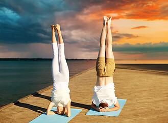 Image showing couple making yoga headstand on mat outdoors