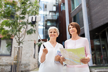 Image showing senior women with map and city guide taking selfie