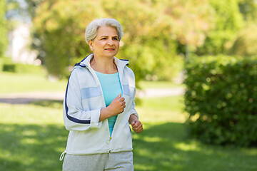 Image showing senior woman running along summer park