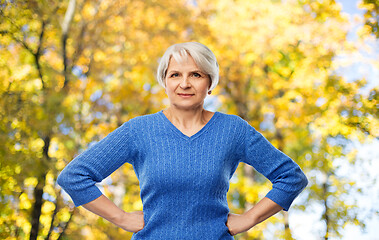 Image showing senior woman with hands on hips in autumn park