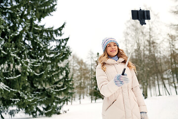 Image showing woman taking picture by selfie stick in winter