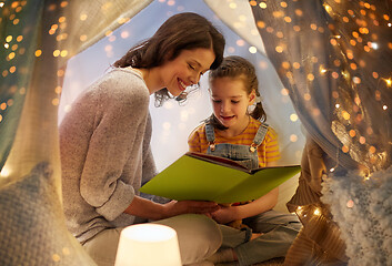 Image showing happy family reading book in kids tent at home