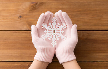 Image showing hands in pale pink gloves holding big snowflake