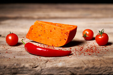 Image showing Red gourmet cheese with tomatos and parika on rough wooden planks