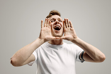 Image showing Isolated on gray young casual man shouting at studio