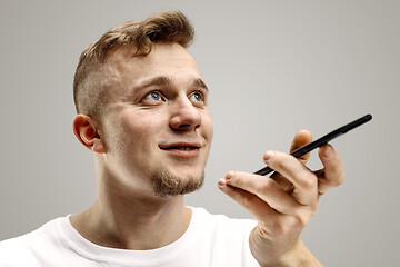 Image showing Indoor portrait of attractive young man holding smartphone