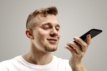 Image showing Indoor portrait of attractive young man holding smartphone