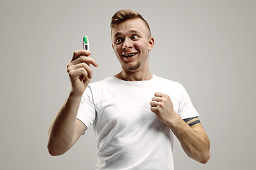 Image showing Happy man looking at pregnancy test at studio