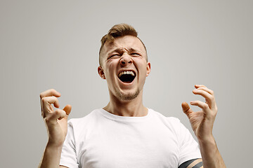 Image showing The young emotional angry man screaming on garay studio background