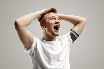 Image showing The young emotional angry man screaming on garay studio background