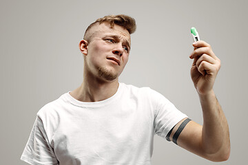 Image showing Upset man looking in pregnancy test. Frustrated model