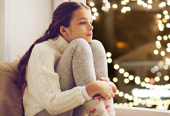 Image showing sad girl sitting at home window on christmas