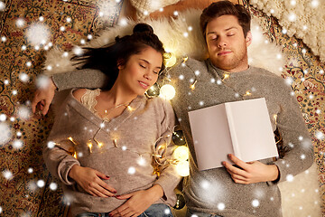 Image showing happy couple with garland lying on floor at home