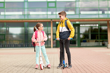 Image showing happy school children with backpacks and scooters