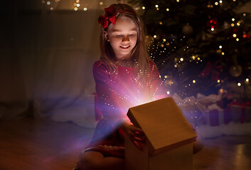 Image showing smiling girl opening christmas gift at night