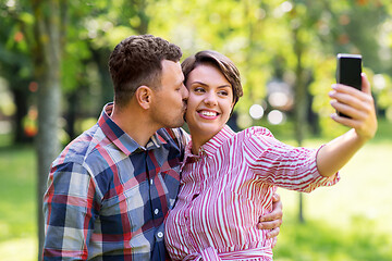 Image showing happy couple in park taking selfie by smartphone