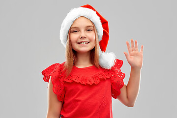 Image showing smiling girl in snata helper hat waving hand