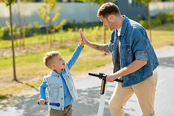 Image showing father and son with scooters making high five