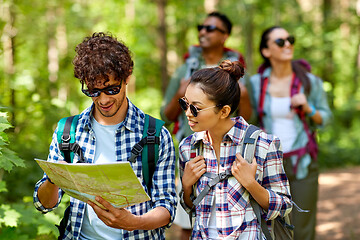 Image showing friends with map and backpacks hiking in forest