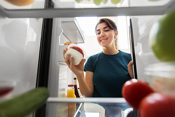 Image showing happy woman taking food from fridge at home