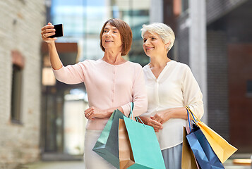 Image showing old women with shopping bags taking selfie in city