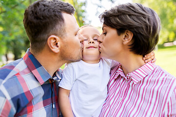 Image showing mother and father kissing their little son at park