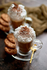 Image showing Two tall glasses with hot chocolate, whipped cream and cinnamon powder on top