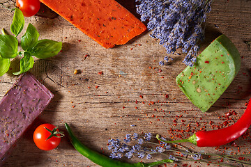 Image showing Three different cheeses on rough wooden planks: lavender, paprika and pesto cheeses