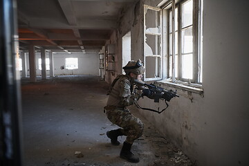 Image showing soldier in action near window changing magazine and take cover