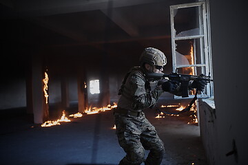 Image showing soldier in action near window changing magazine and take cover