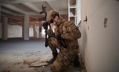 Image showing soldier in action near window changing magazine and take cover