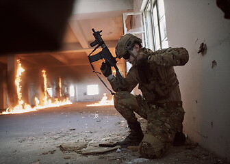 Image showing soldier in action near window changing magazine and take cover