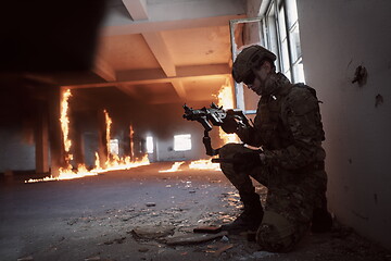 Image showing soldier in action near window changing magazine and take cover