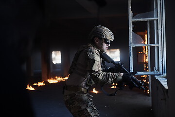 Image showing soldier in action near window changing magazine and take cover