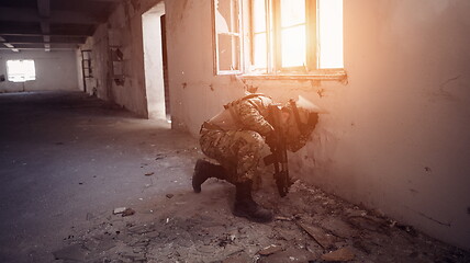 Image showing soldier in action near window changing magazine and take cover