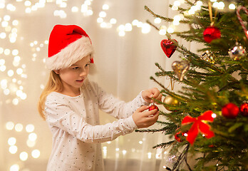 Image showing happy girl in santa hat decorating christmas tree