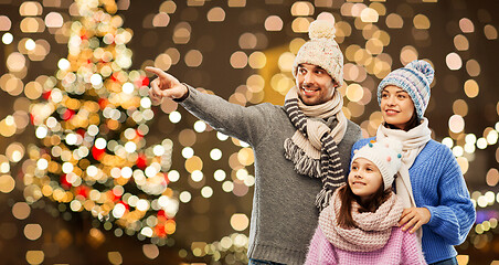 Image showing happy family in winter hats over christmas lights