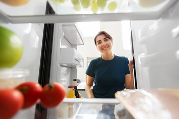 Image showing happy woman at open fridge at home kitchen