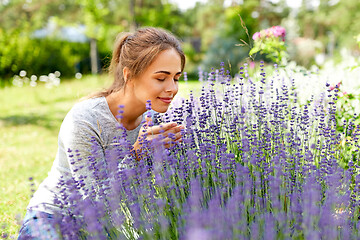 Image showing young woman smelling lavender flowers in garden