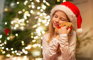 Image showing smiling girl in santa hat with christmas gift