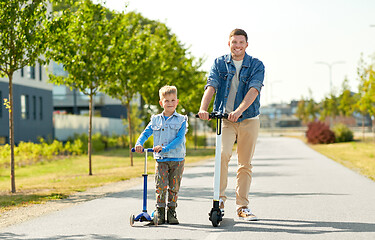 Image showing father and little son riding scooters in city