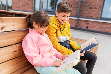 Image showing school children reading books sitting on bench
