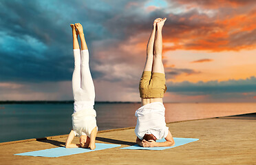 Image showing couple making yoga headstand on mat outdoors