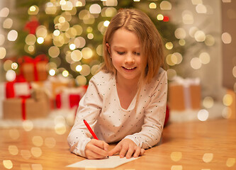 Image showing smiling girl writing christmas wish list at home