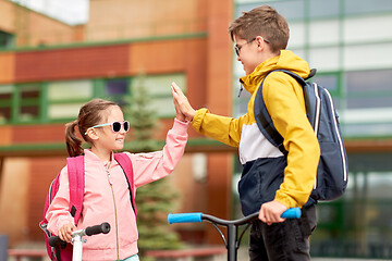 Image showing happy school children with backpacks and scooters